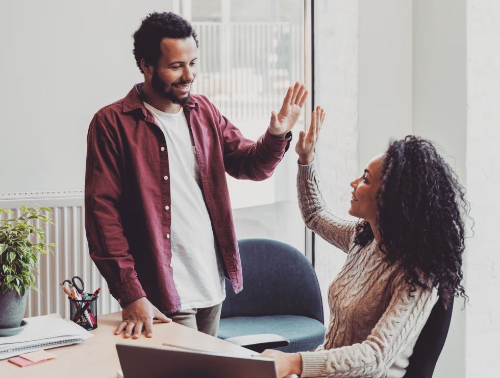 Deux collègues de bureau échangeant un high five pour célébrer une réussite professionnelle