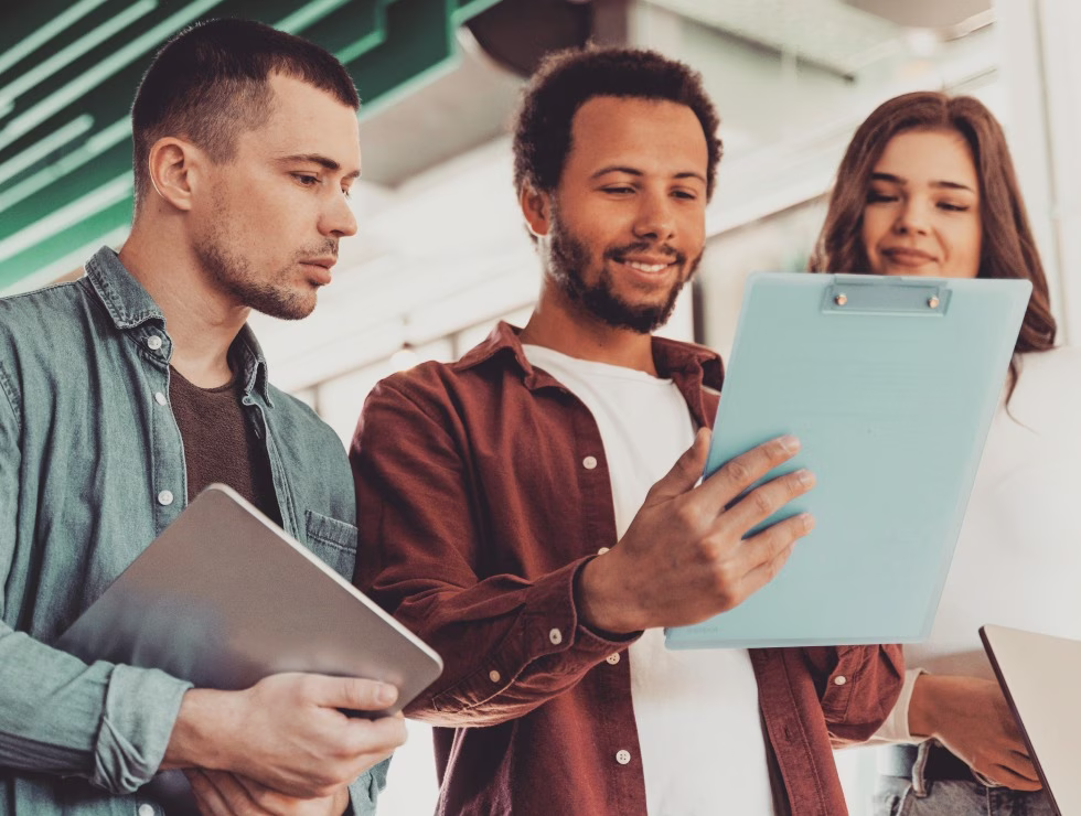 Trois jeunes professionnels analysant un document ensemble dans un environnement de travail moderne